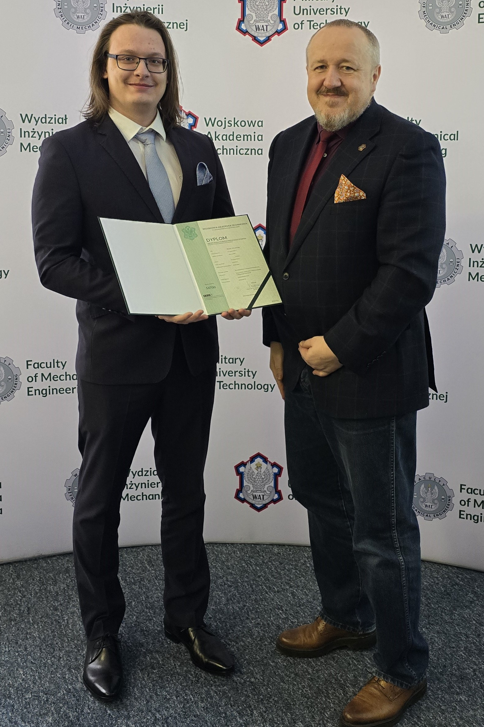 Fot. 4. Michał Polakow i dziekan Jerzy Małachowski na tle ścianki wydziałowej z logiem WIM WAT.